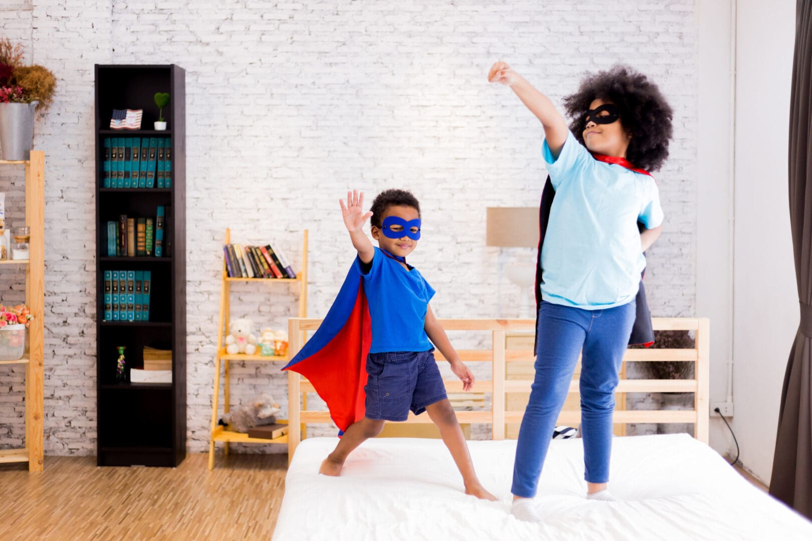 Two children dressed as superheroes in a room.