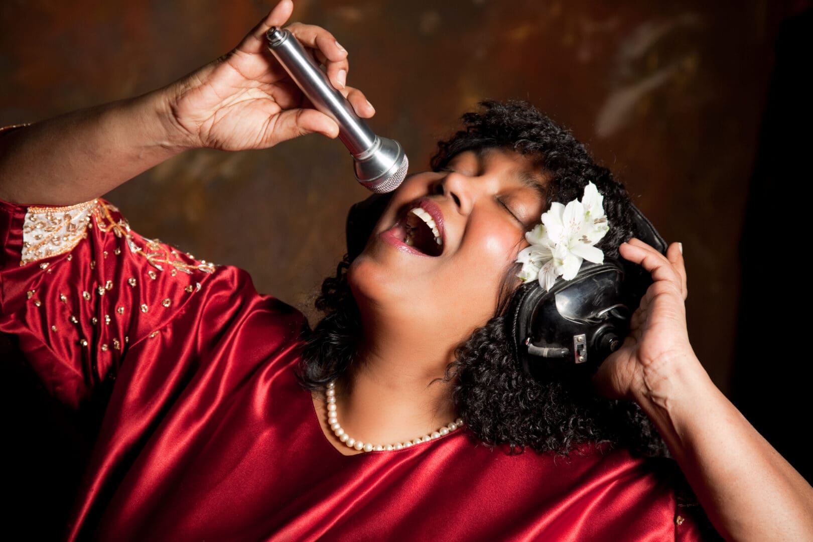 A woman singing into a microphone with her eyes closed.