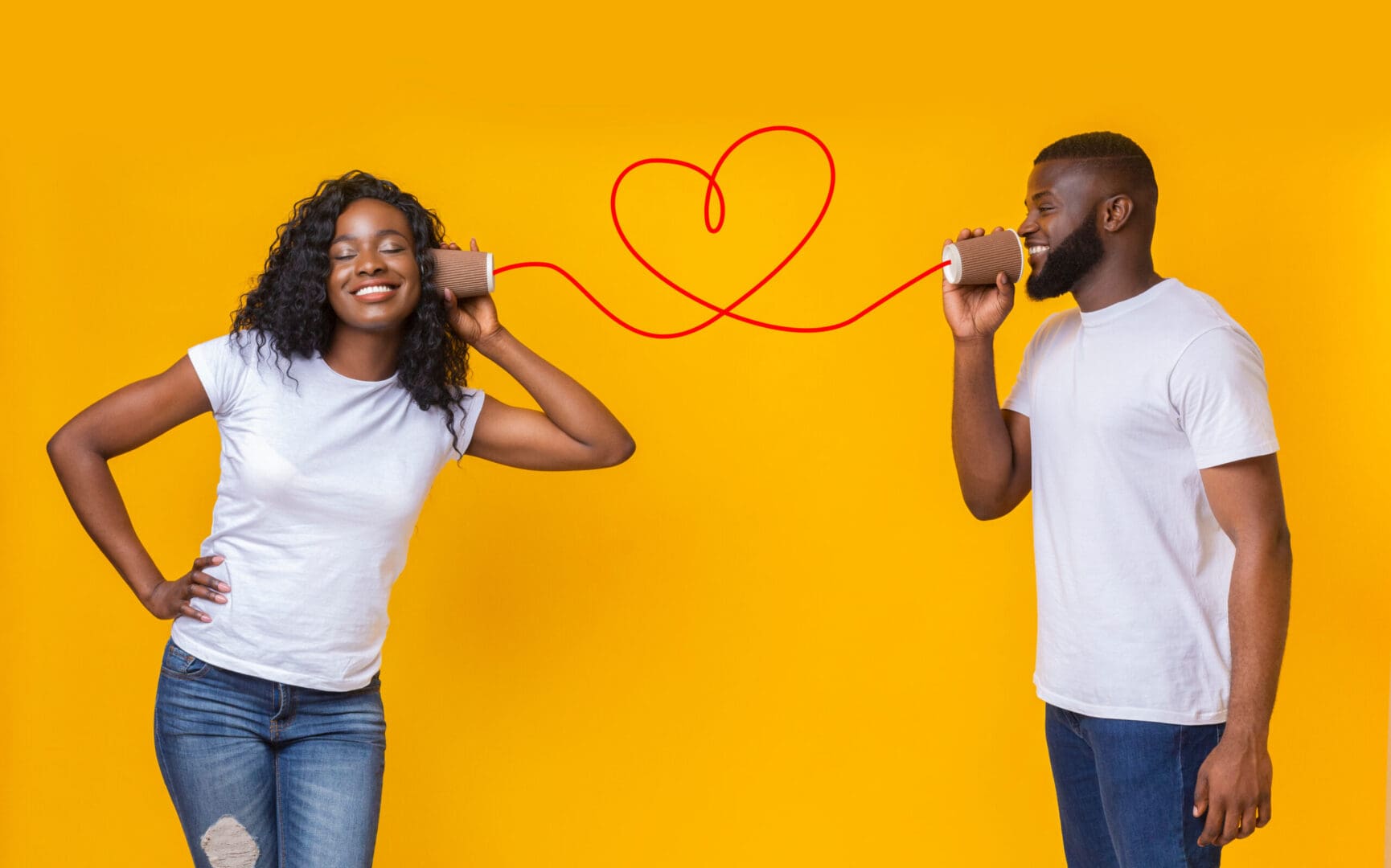 A man and woman holding their ears with one hand, while the other holds a cord in the shape of a heart.