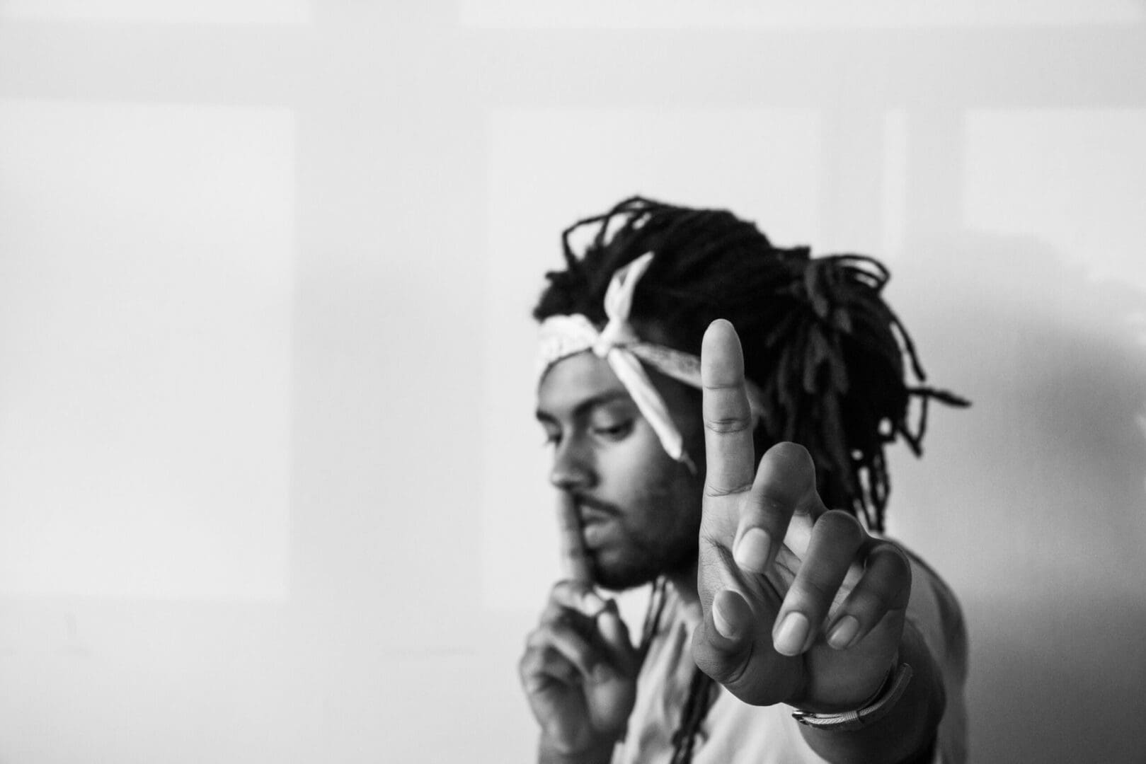 A man with dreadlocks is holding up his middle finger.