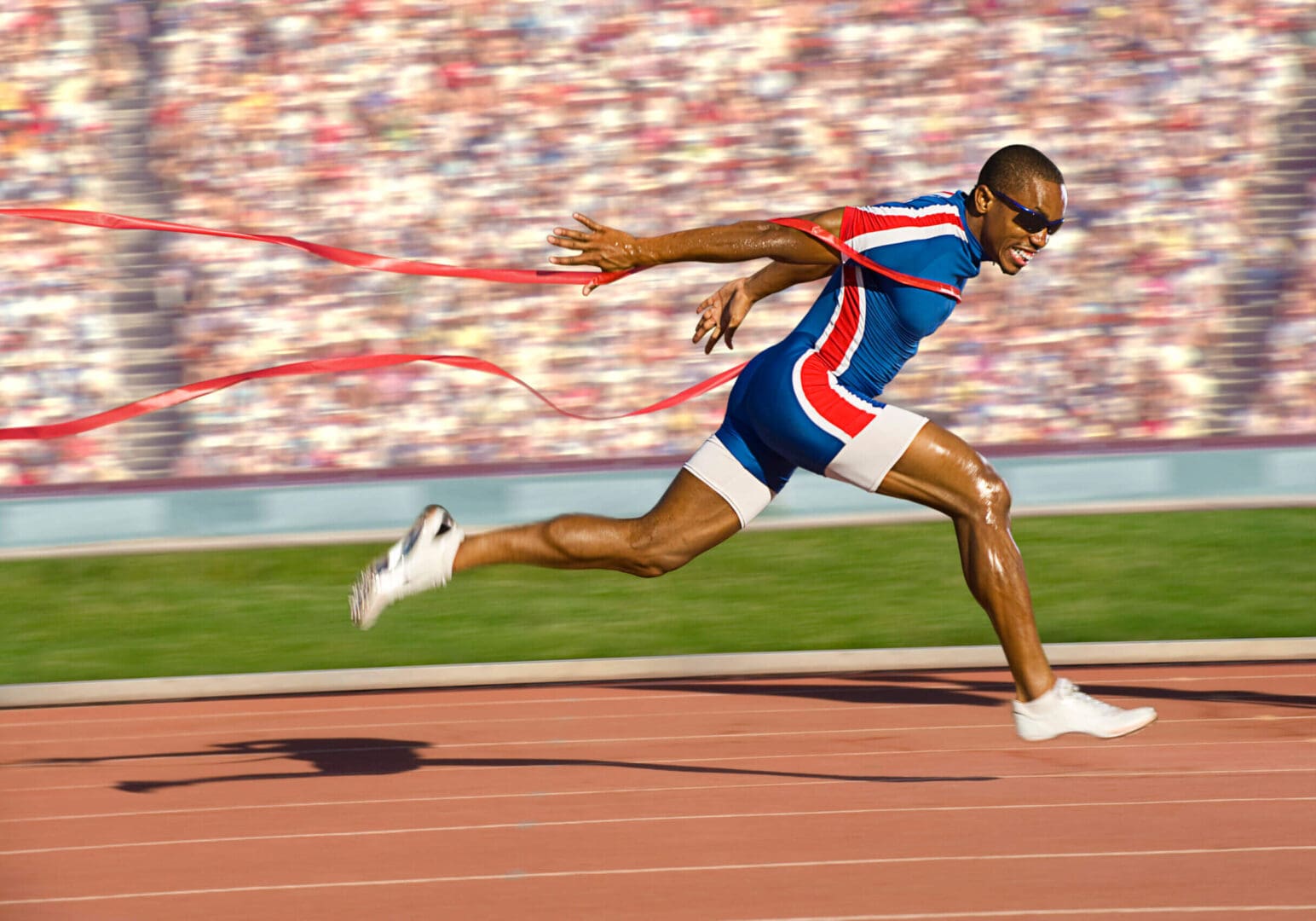 A man running on the track with a red ribbon.