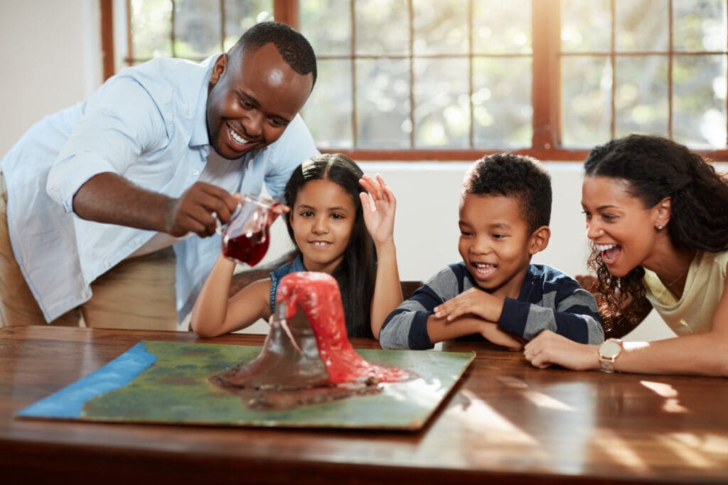 A man and three children are playing with a toy volcano.