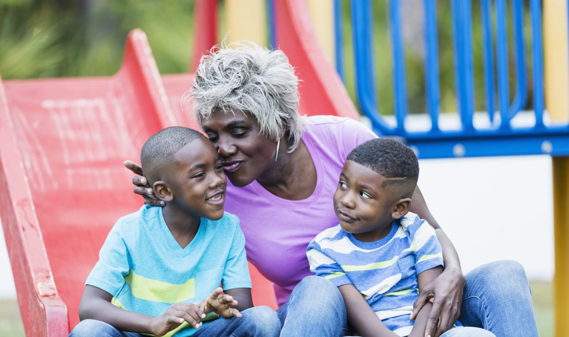 A woman sitting on the ground with two children.