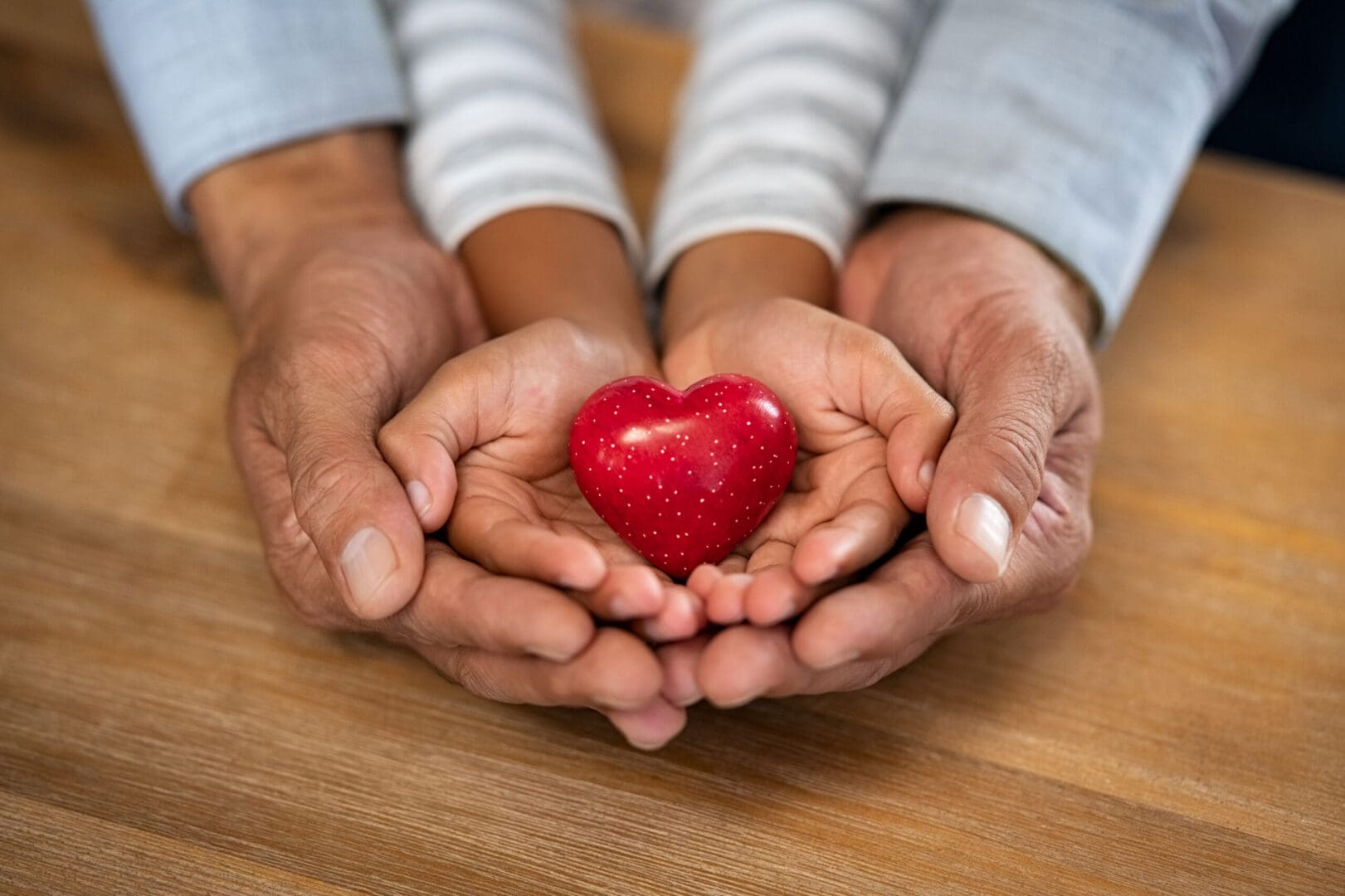 A couple of people holding hands with a heart in their hands.