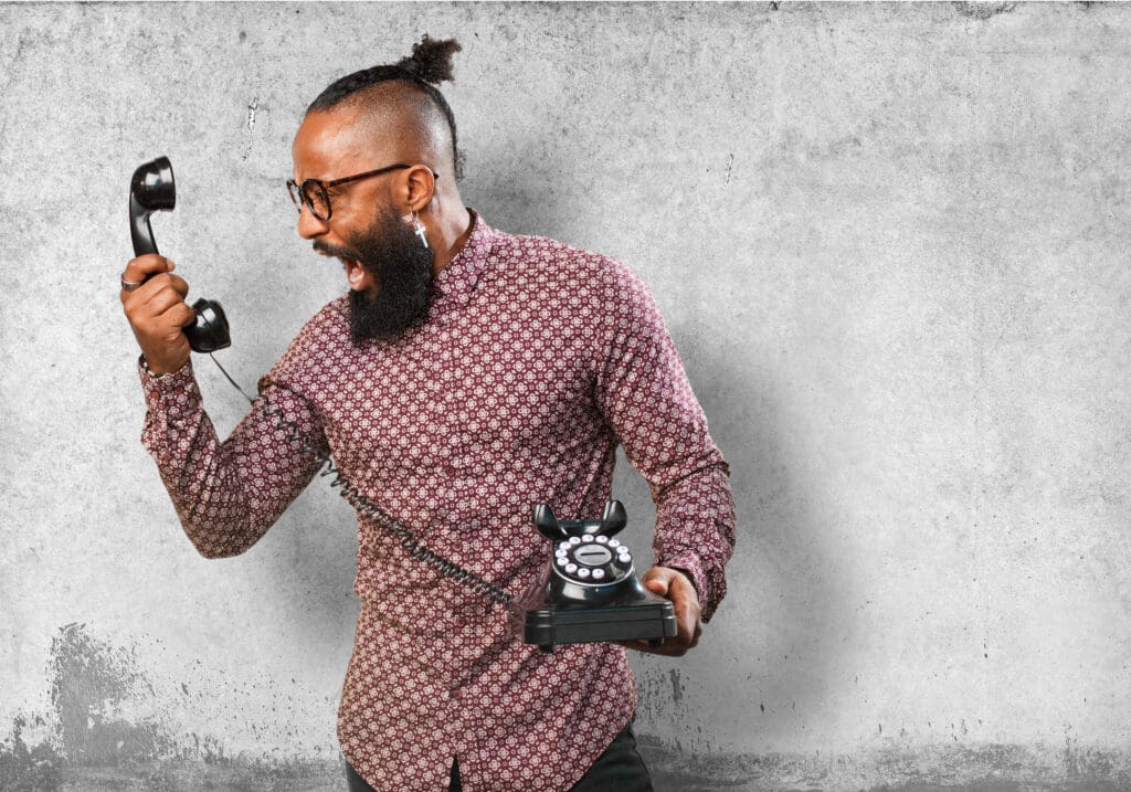 A man with a beard and a tie on his head holding a phone.