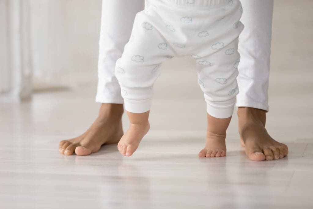 A baby is standing on the ground with his feet