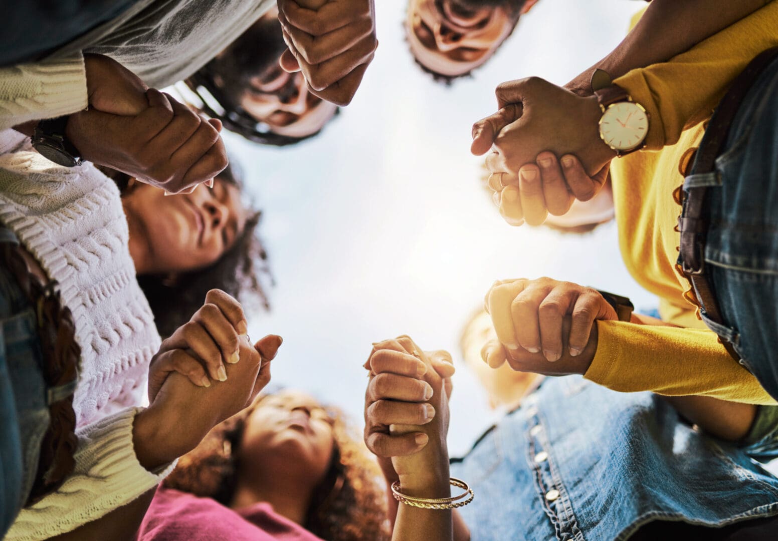 A group of people holding hands in the middle of a circle.