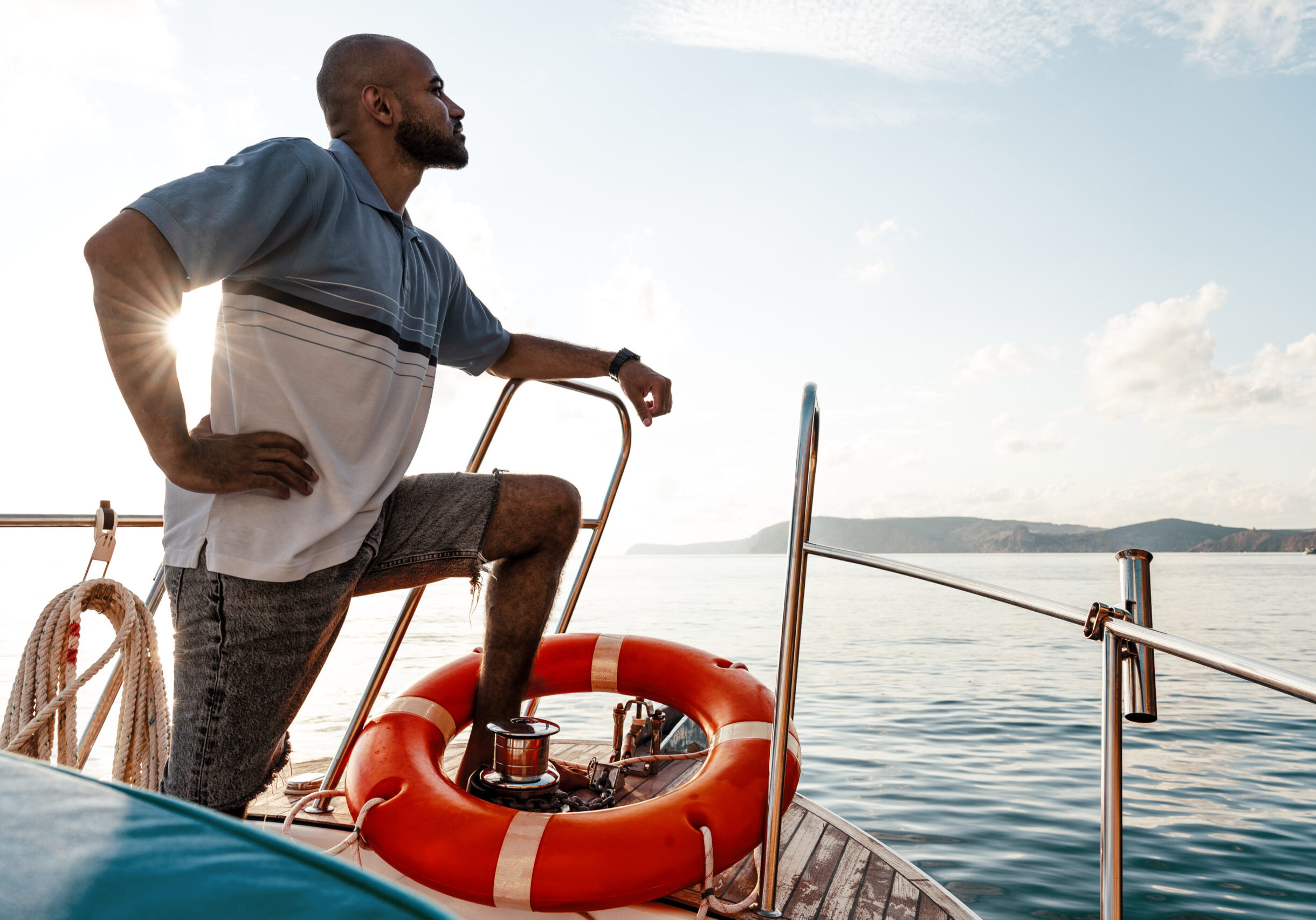 Young african american man relaxing on a sailboat in open sea at sunset, close up