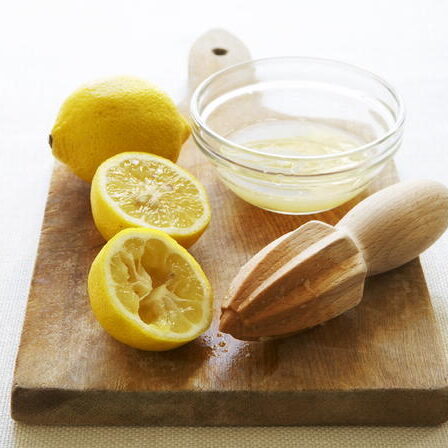 A wooden board with lemons and a juicer on it.