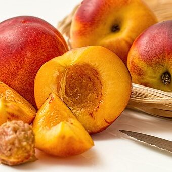 A close up of some peaches and a knife